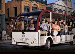 A group of people is enjoying a tour on a white open-sided vehicle labeled 