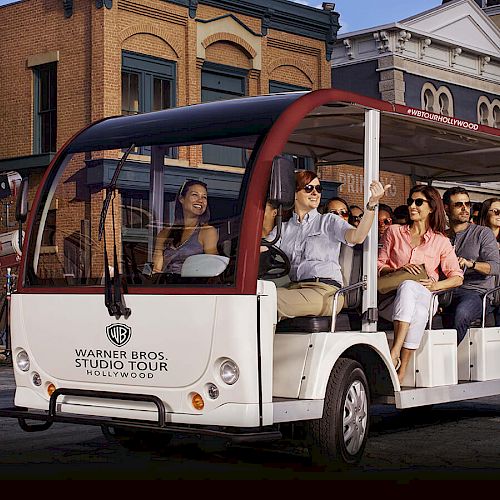 A group of people is enjoying a tour on a white open-sided vehicle labeled 